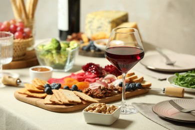 Photo of Red wine and different snacks served on table