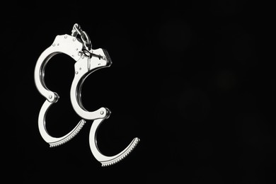 Photo of Metal chain handcuffs on black background, closeup. Space for text