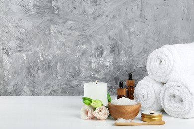 Photo of Spa composition with cosmetic products and towels on white table. Space for text