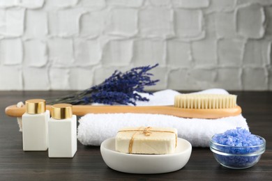 Photo of Spa treatment. Composition with cosmetic products and towel on wooden table