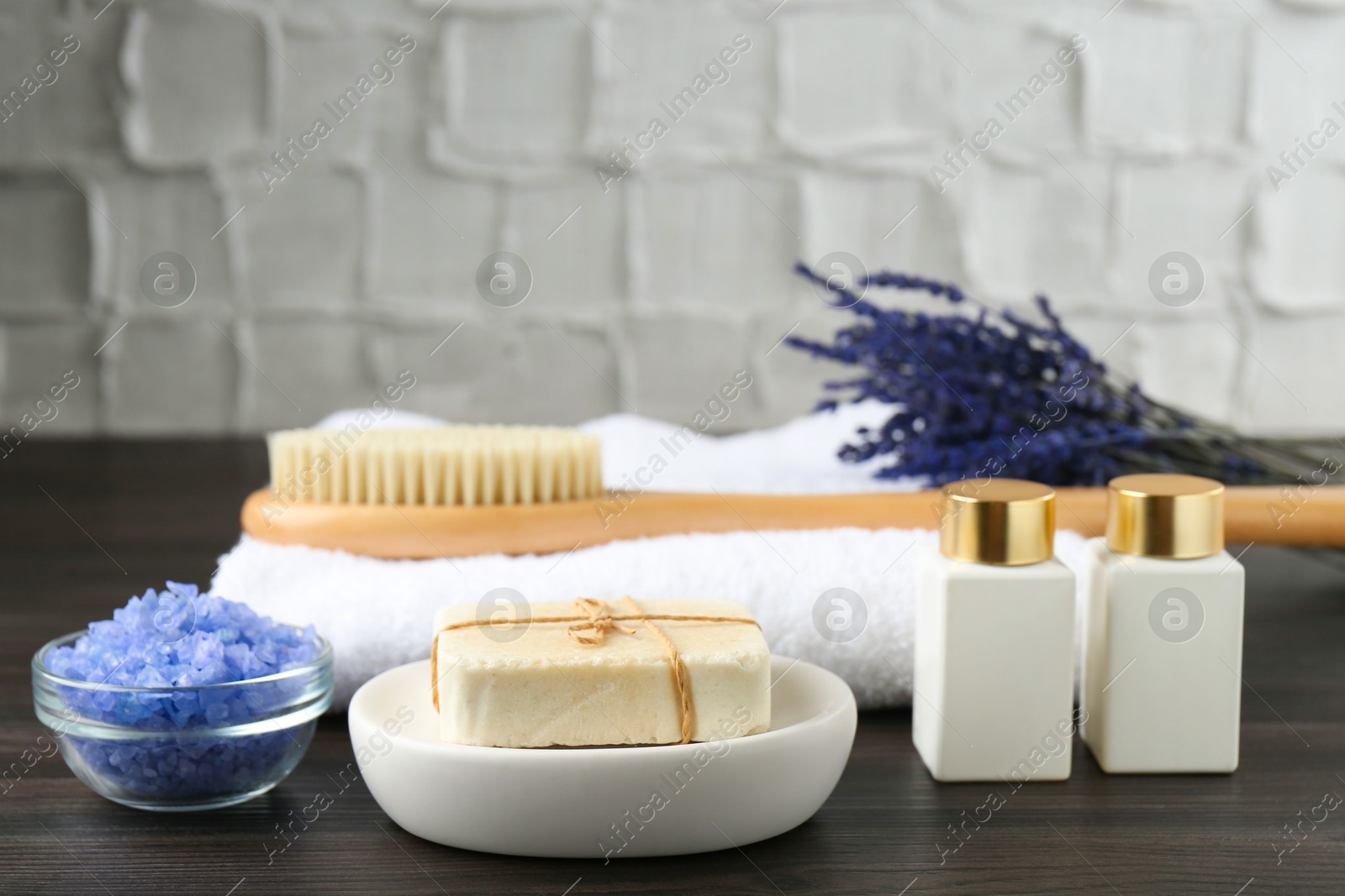 Photo of Spa treatment. Composition with cosmetic products and towel on wooden table