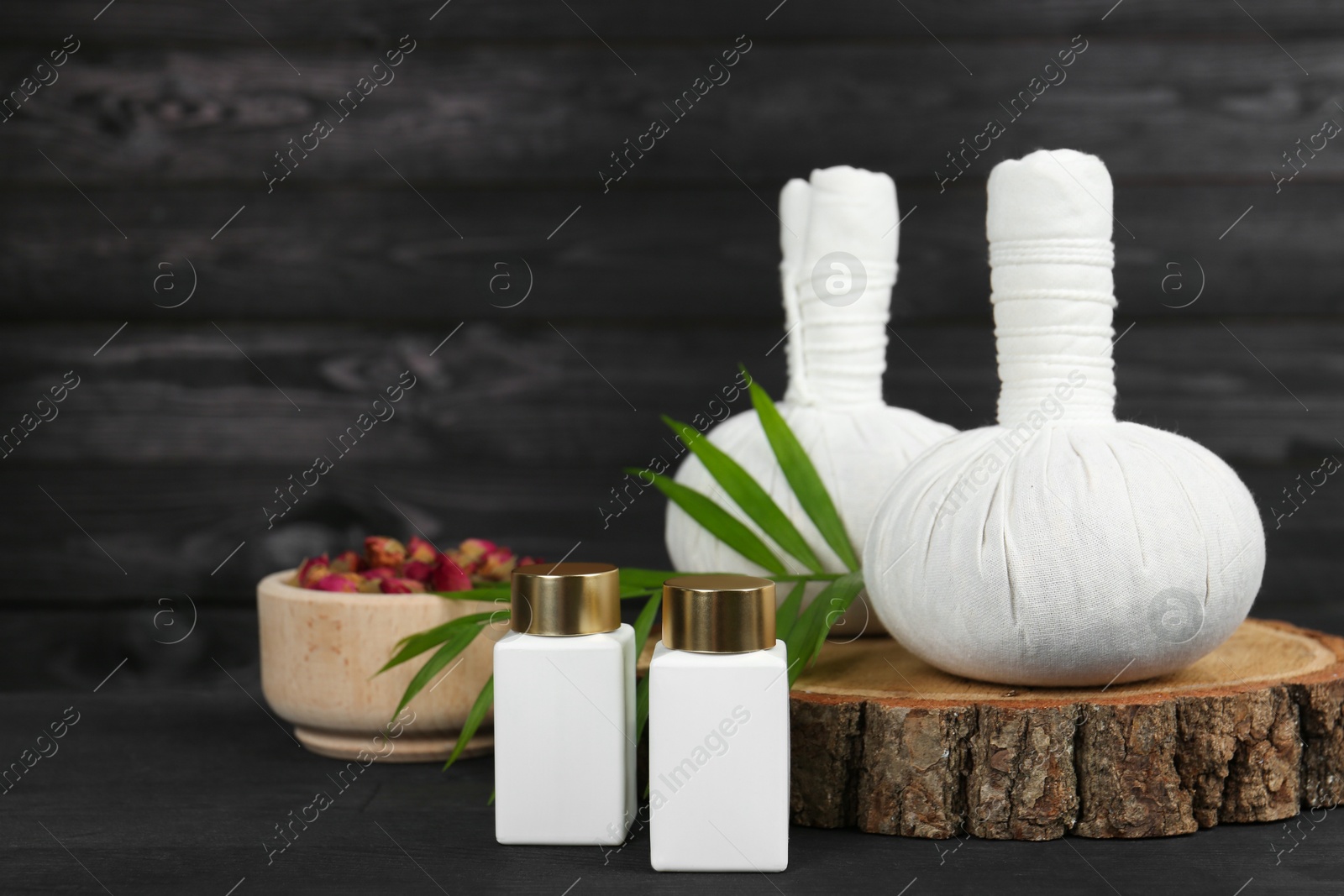 Photo of Composition with cosmetic products and massage bags for spa treatment on black wooden table