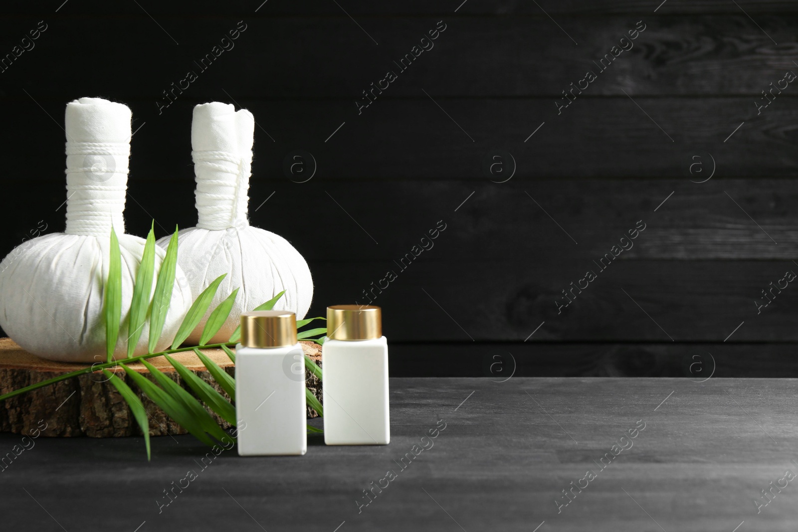 Photo of Composition with cosmetic products and massage bags for spa treatment on black wooden table, space for text