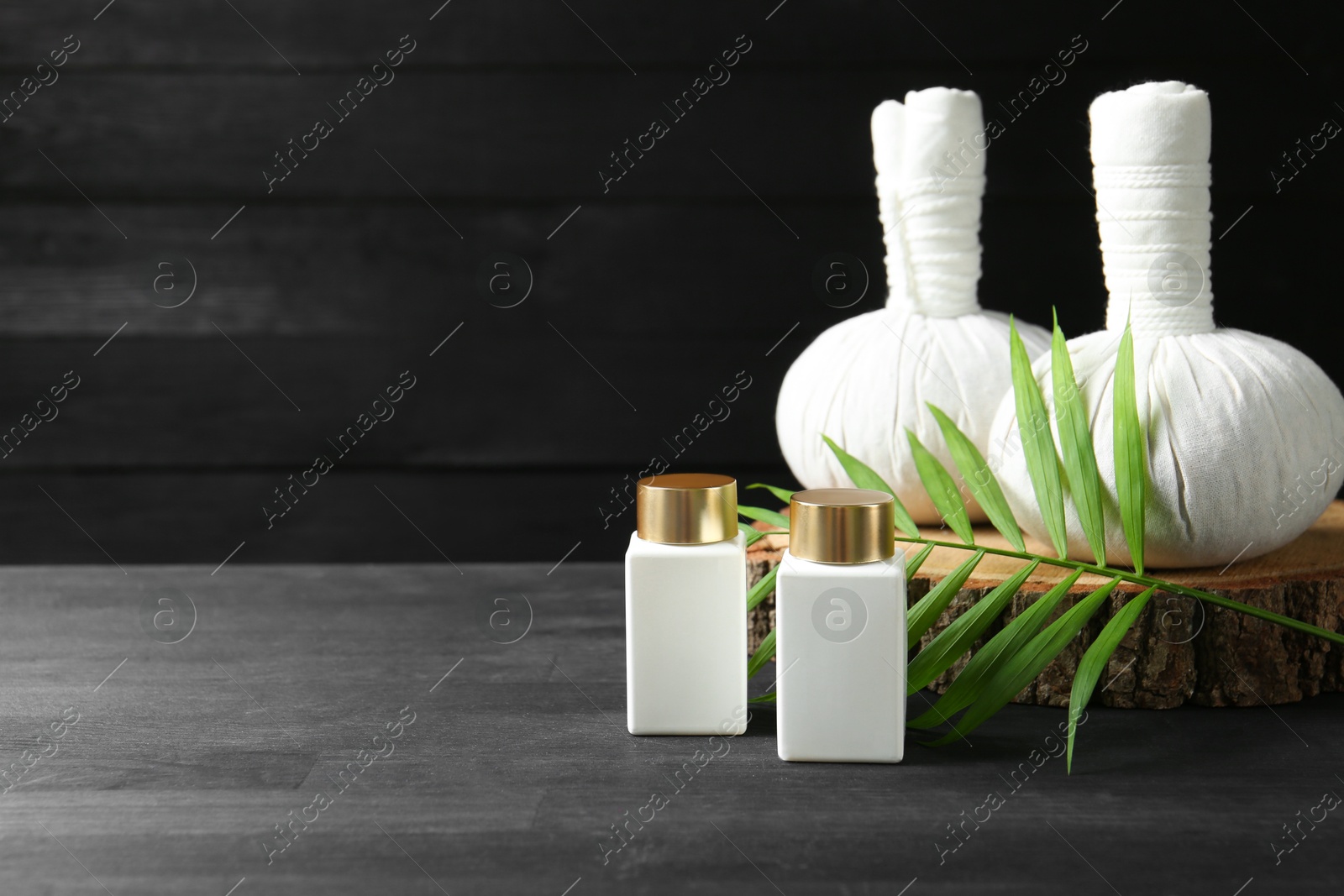 Photo of Composition with cosmetic products and massage bags for spa treatment on black wooden table, space for text