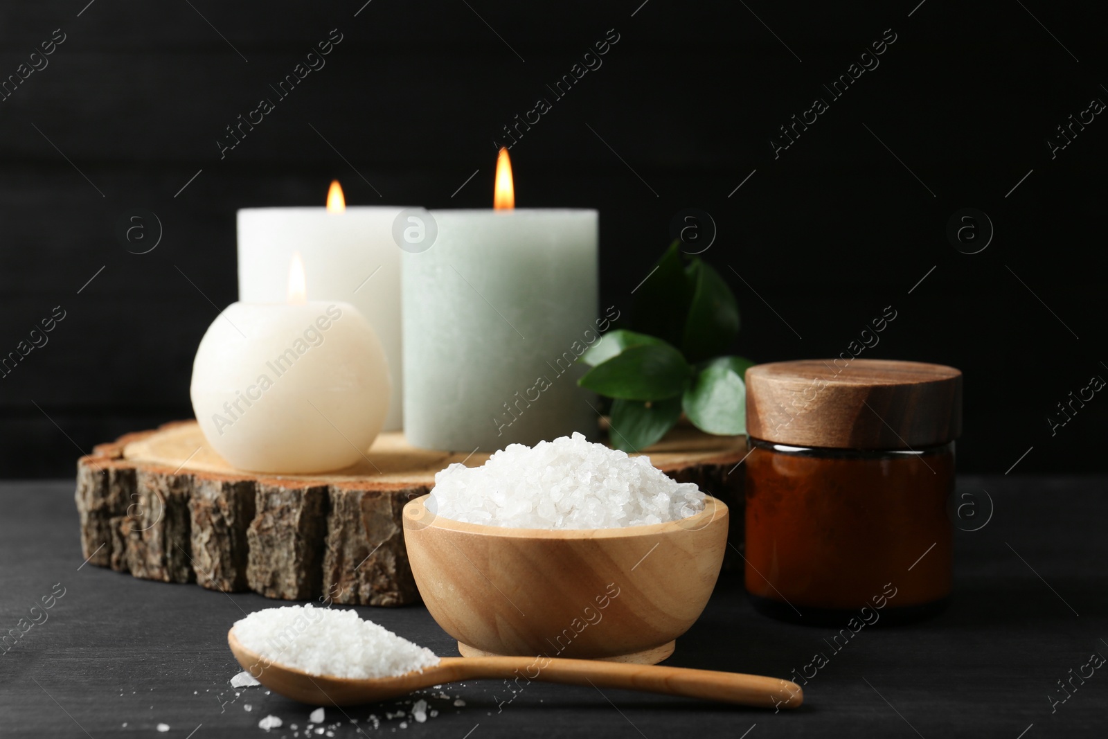 Photo of Composition with cosmetic products and candles for spa treatment on black wooden table