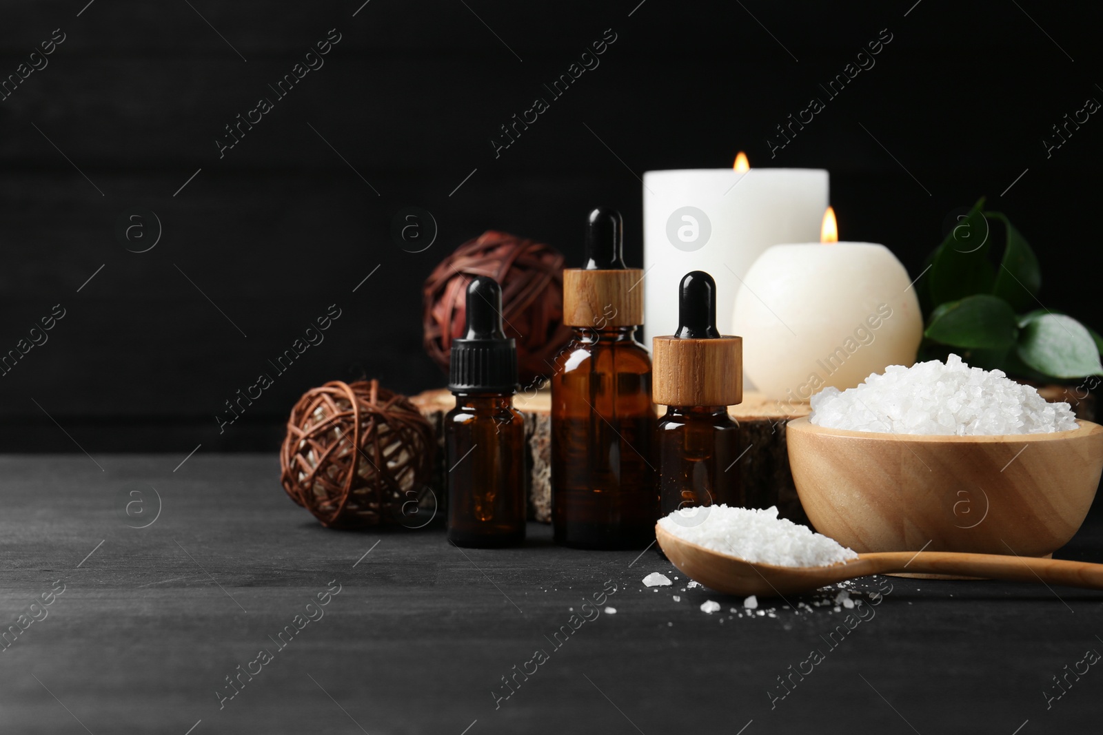 Photo of Composition with cosmetic products and candles for spa treatment on black wooden table, space for text