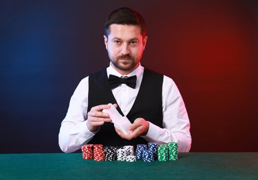 Professional croupier shuffling cards at gambling table