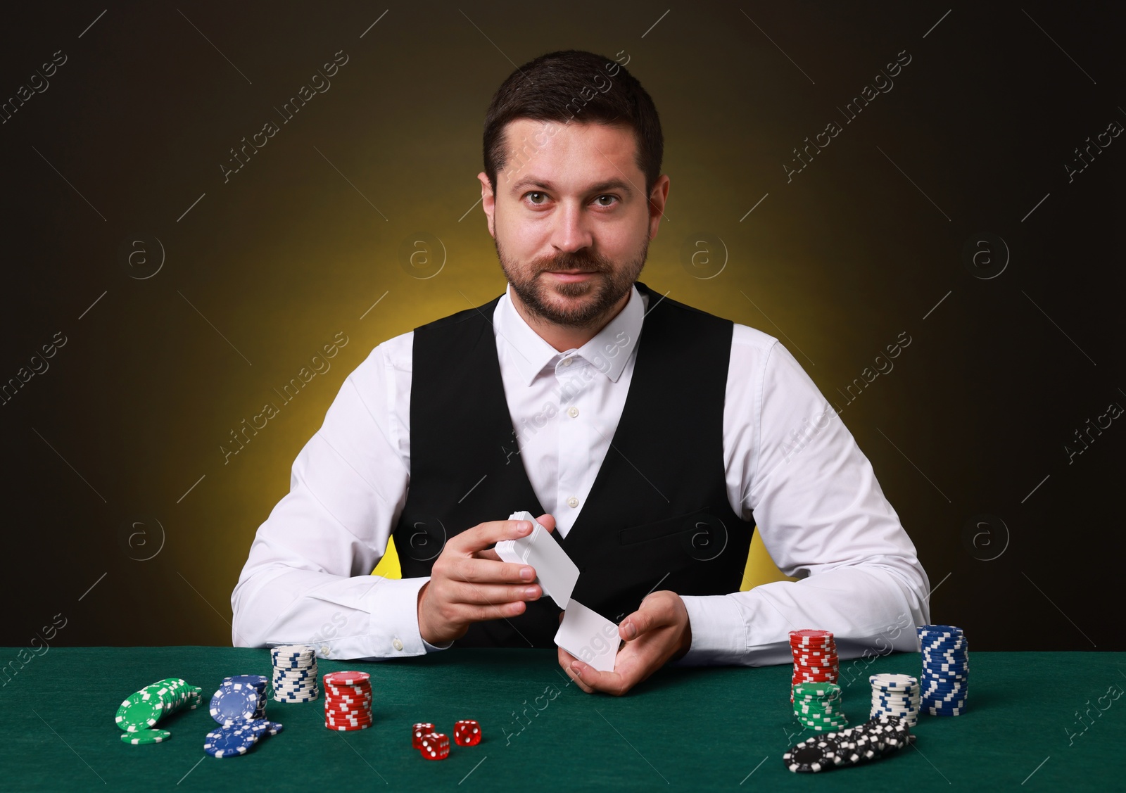 Photo of Professional croupier shuffling cards at gambling table on dark yellow background