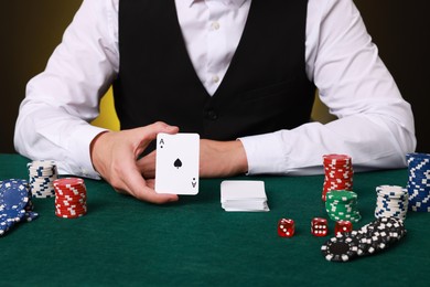 Photo of Professional croupier with playing cards at gambling table, closeup