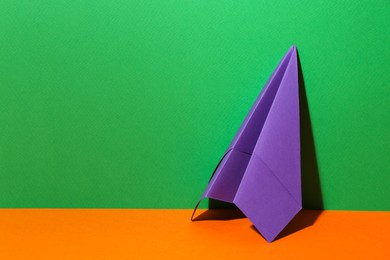 Photo of Handmade purple paper plane on color background. Space for text