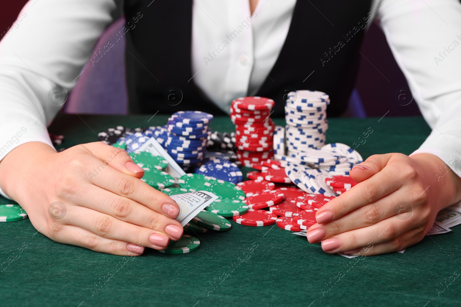 Photo of Professional croupier with casino chips and playing cards at gambling table, closeup