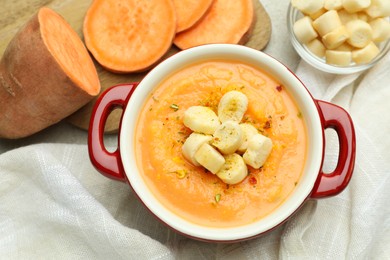 Photo of Delicious sweet potato soup with croutons and fresh vegetable on light table, flat lay