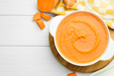 Photo of Delicious sweet potato soup with fresh vegetables on white wooden table, top view. Space for text