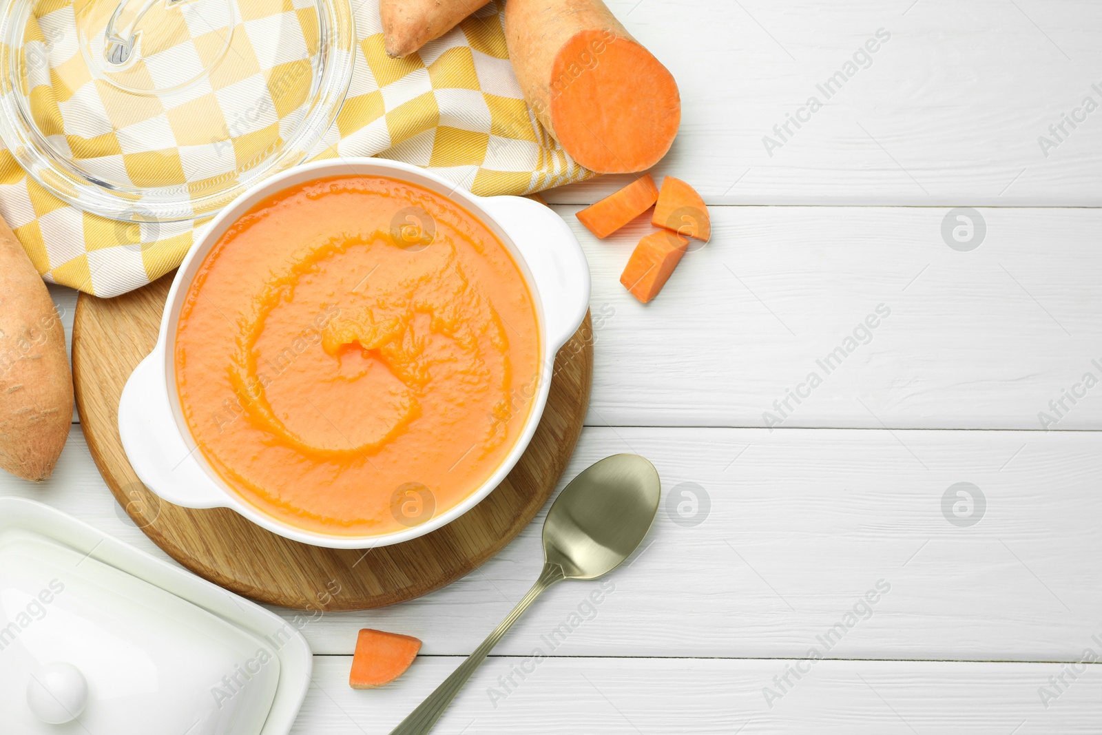 Photo of Delicious sweet potato soup served on white wooden table, flat lay. Space for text