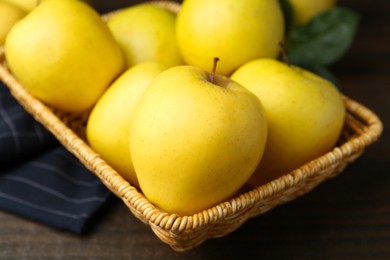 Photo of Fresh yellow apples in wicker basket on table, closeup