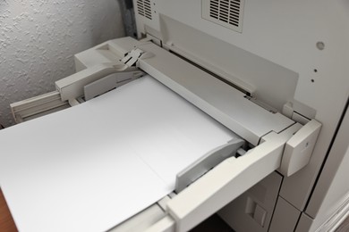 Photo of Modern printer with paper indoors, closeup. Printing house