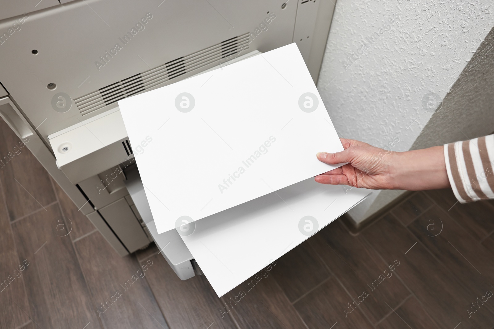 Photo of Woman using modern printer indoors, above view. Printing house