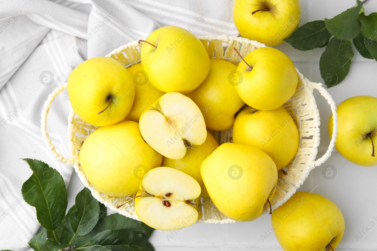 Photo of Fresh ripe yellow apples and leaves on white tiled table, flat lay