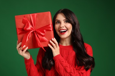 Beautiful woman with Christmas gift on green background