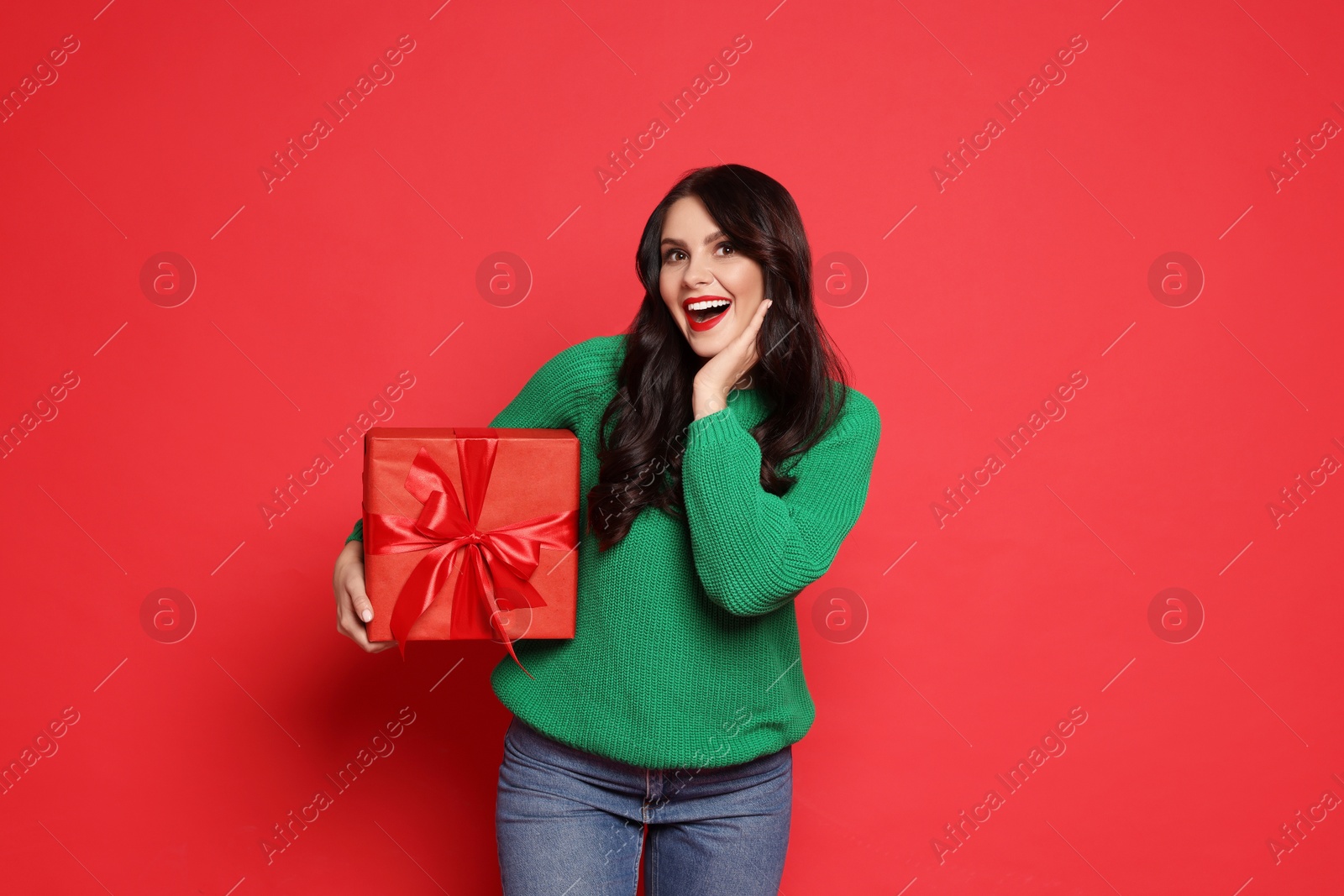 Photo of Happy woman with Christmas present on red background