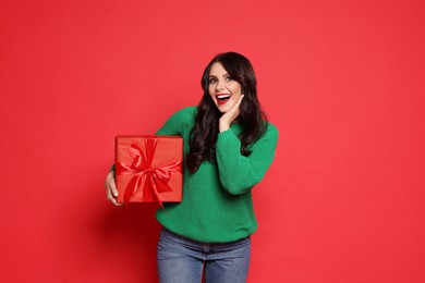 Photo of Happy woman with Christmas present on red background