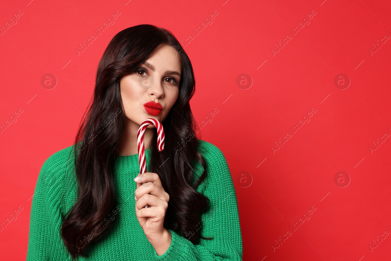 Photo of Beautiful woman with candy cane on red background, space for text. Christmas celebration