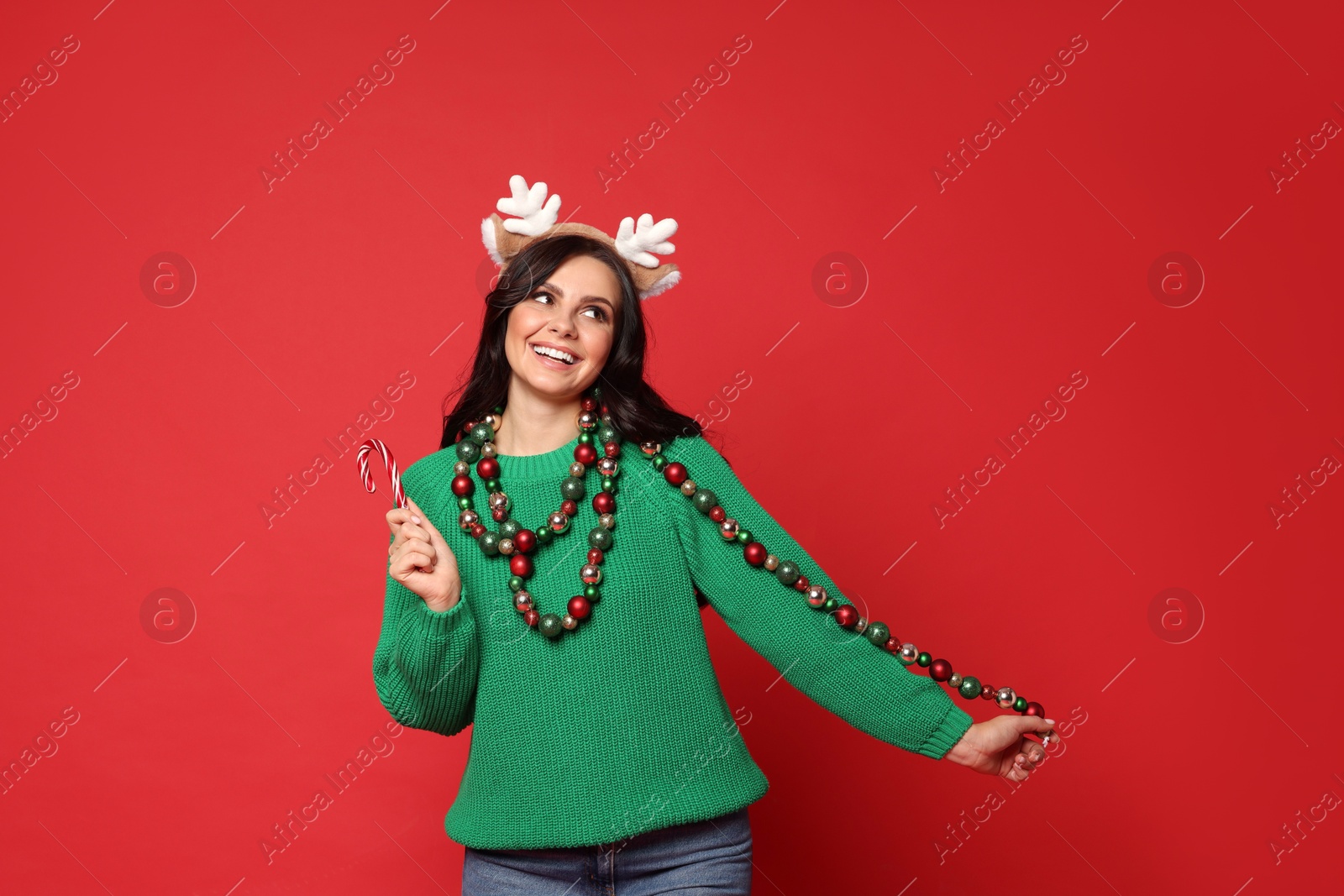 Photo of Beautiful woman with Christmas accessories and candy cane on red background