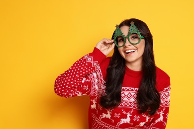 Happy woman with party glasses on yellow background. Christmas celebration