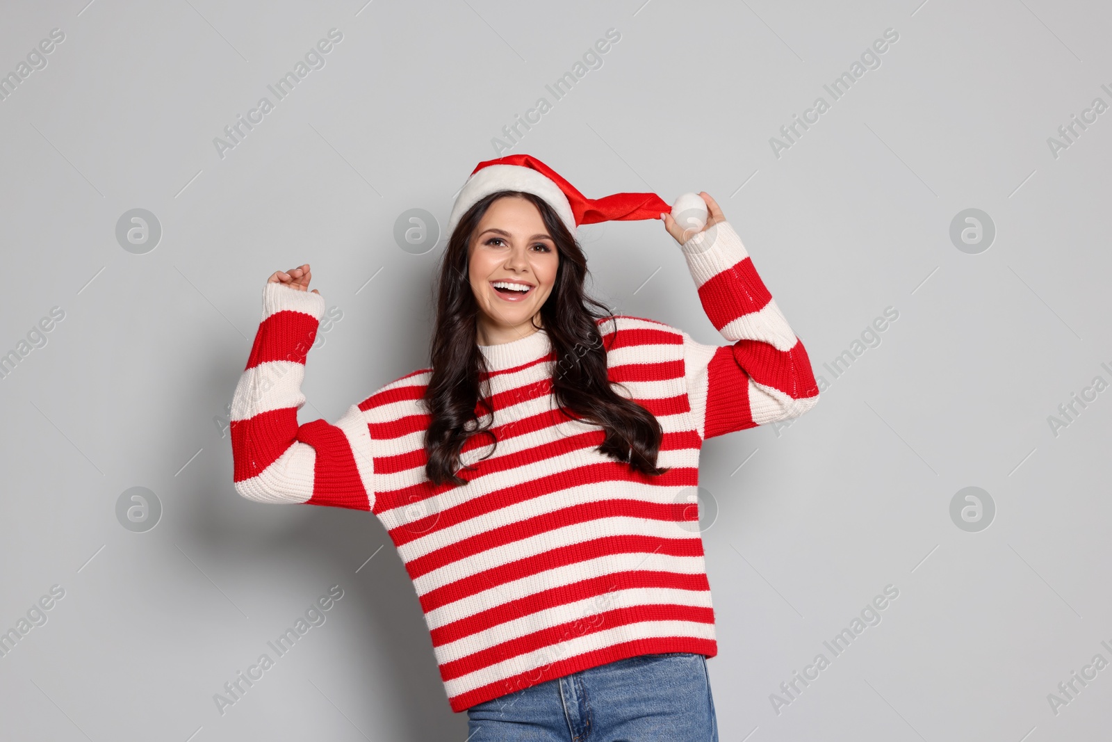 Photo of Beautiful woman in Santa hat on light grey background. Christmas celebration