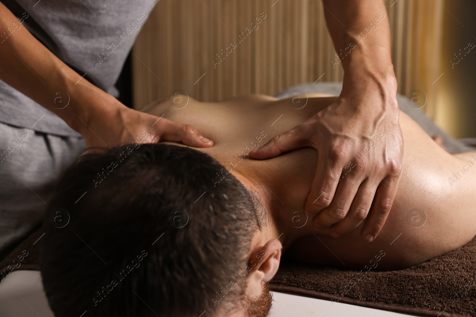 Photo of Professional physiotherapist doing neck massage for his client indoors, closeup