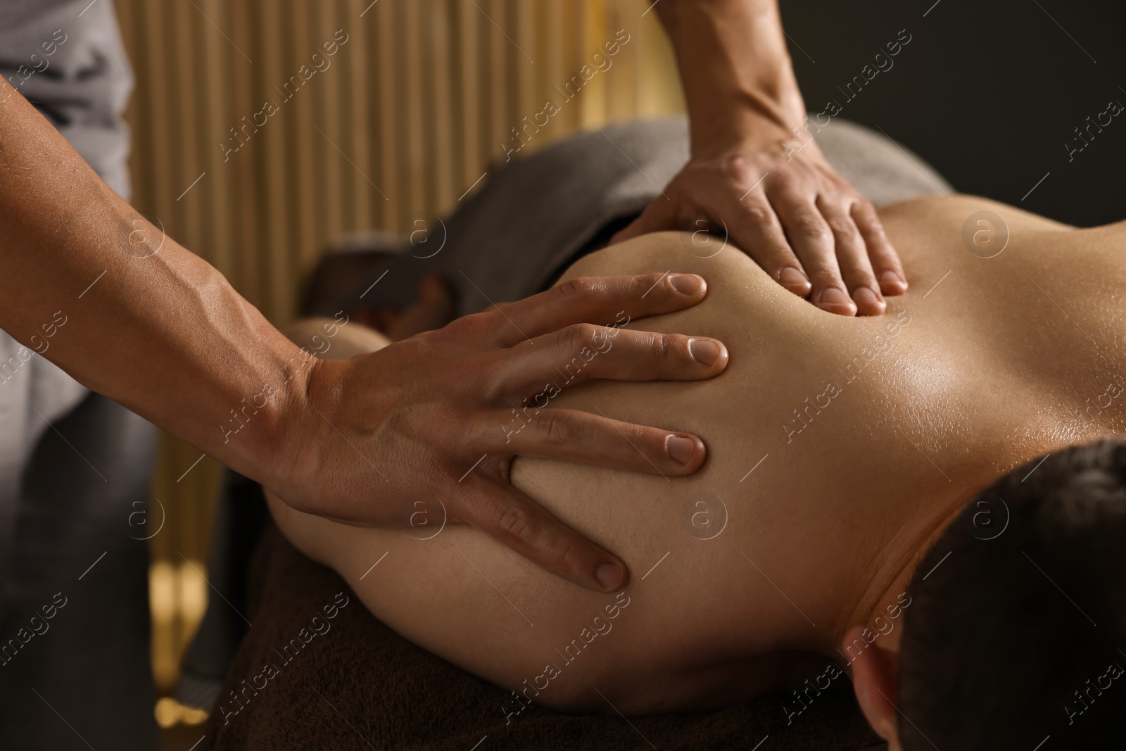 Photo of Professional physiotherapist doing shoulder massage for his client indoors, closeup