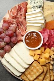 Photo of Different types of cut cheese and other snacks on grey textured table, top view