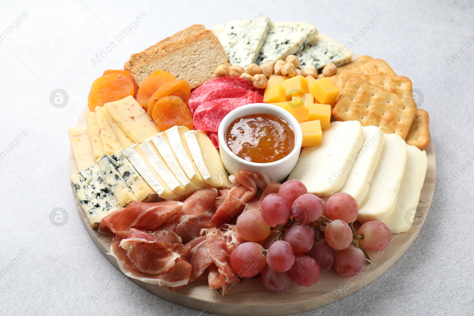 Photo of Different types of cut cheese and other snacks on light textured table, closeup