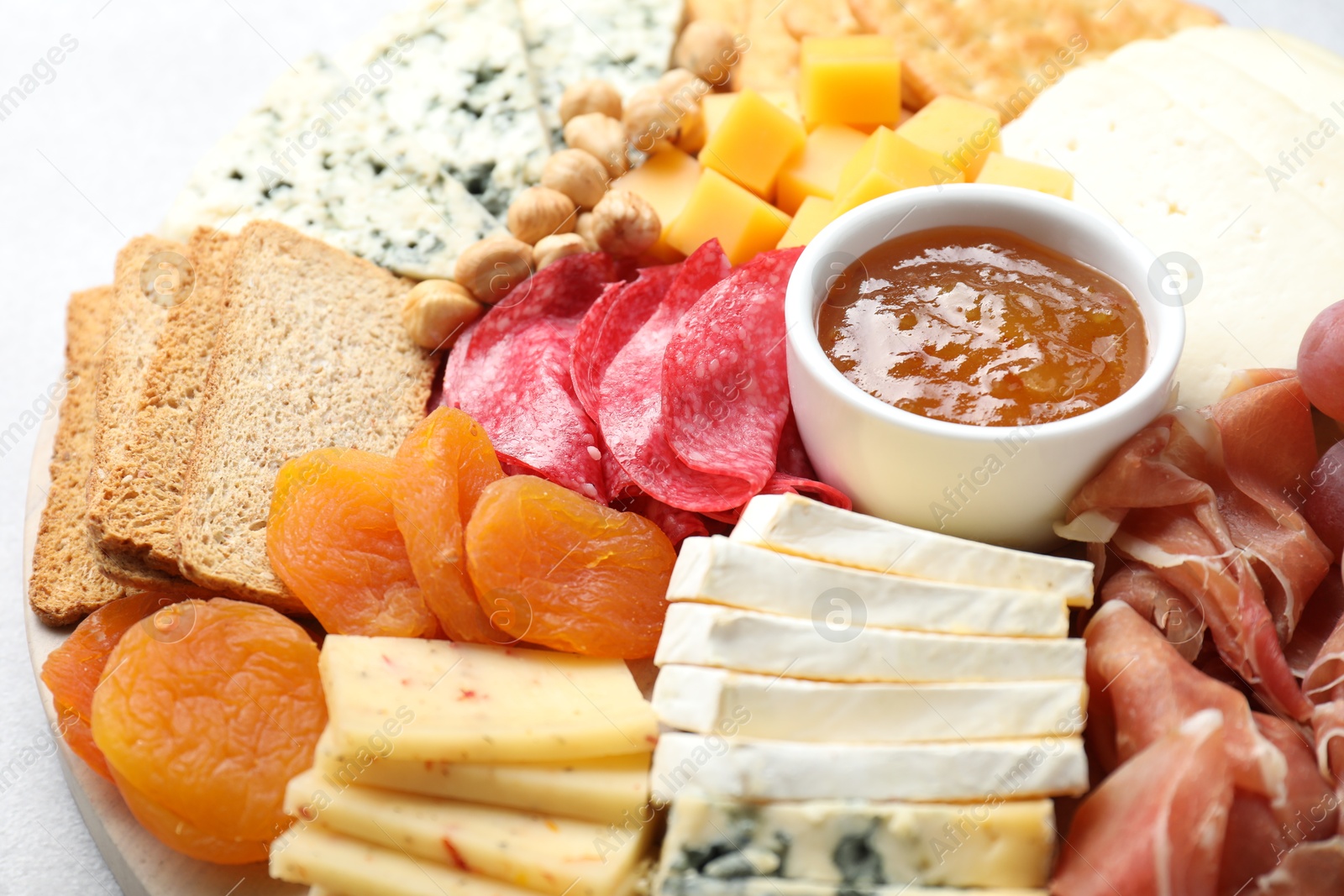 Photo of Different types of cut cheese and other snacks on table, closeup