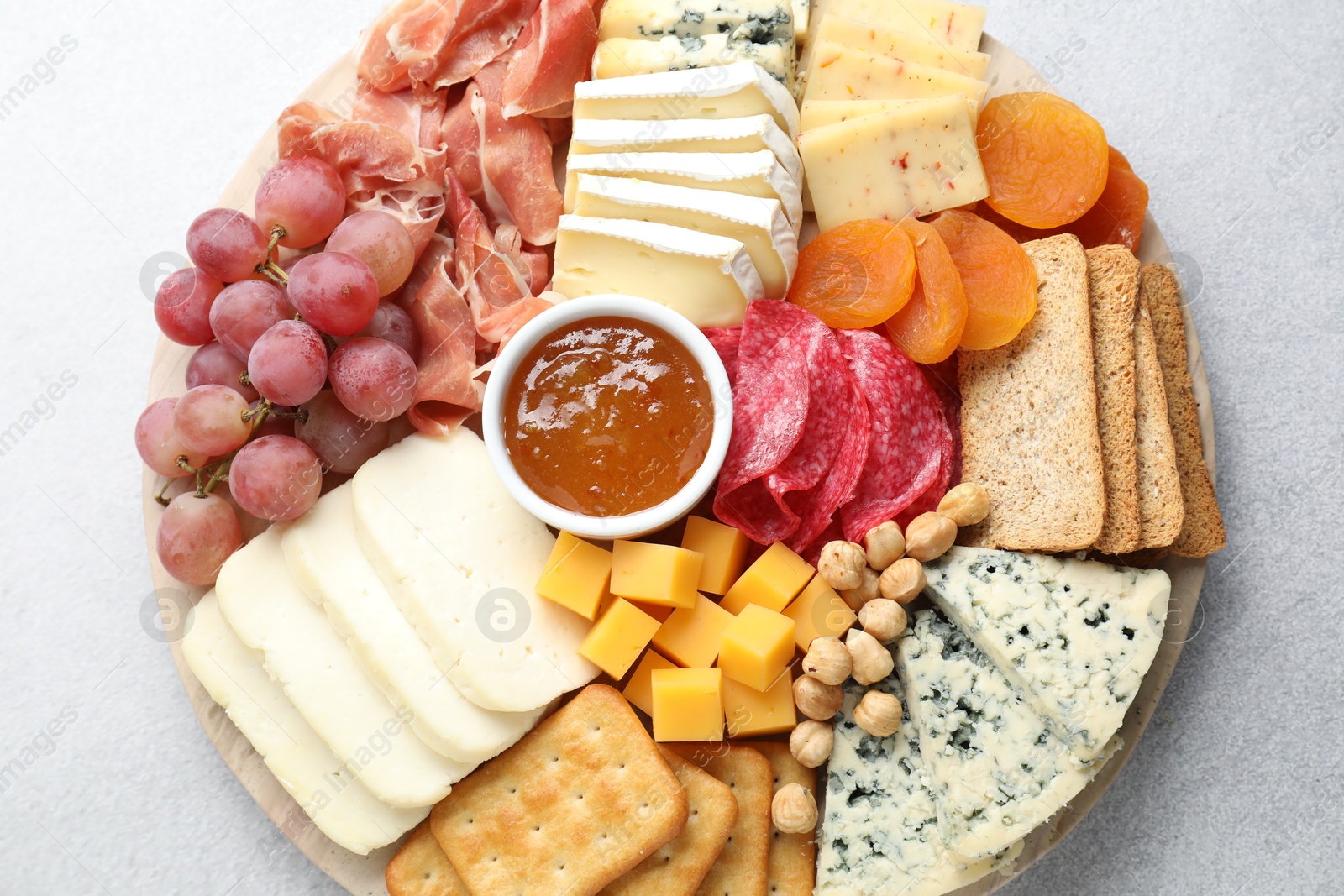 Photo of Different types of cut cheese and other snacks on light textured table, top view