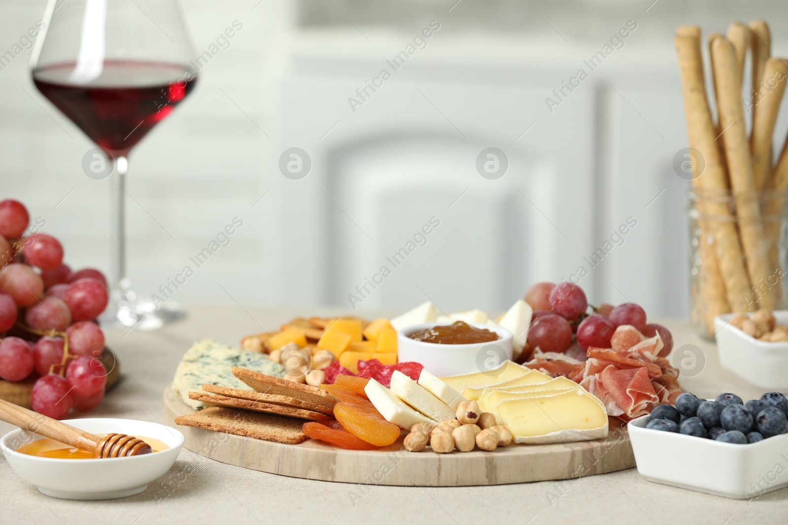 Photo of Different types of cut cheese and other snacks on light textured table, closeup