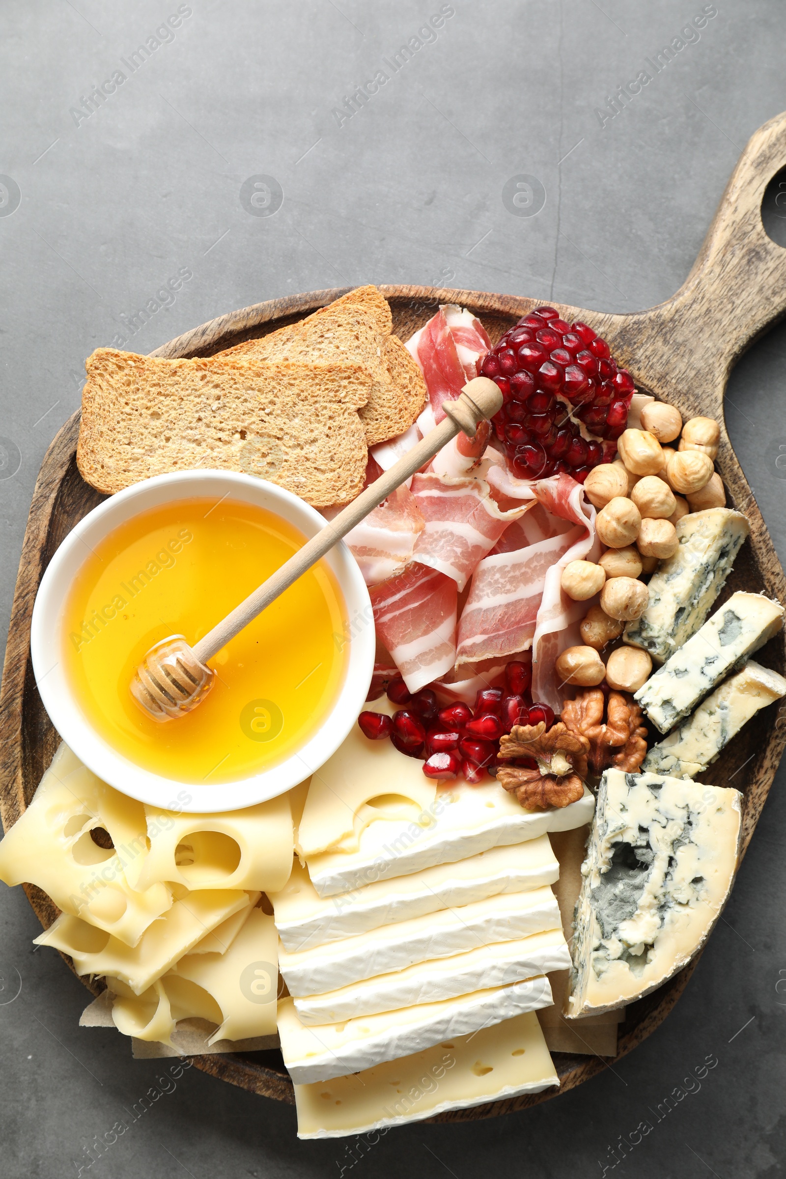 Photo of Different types of cut cheese and other snacks on gray textured table, top view