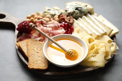 Photo of Different types of cut cheese and other snacks on gray textured table, closeup