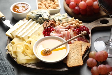 Photo of Different types of cut cheese and other snacks on gray table, closeup