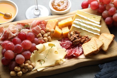 Photo of Different types of cut cheese and other snacks on gray table, closeup