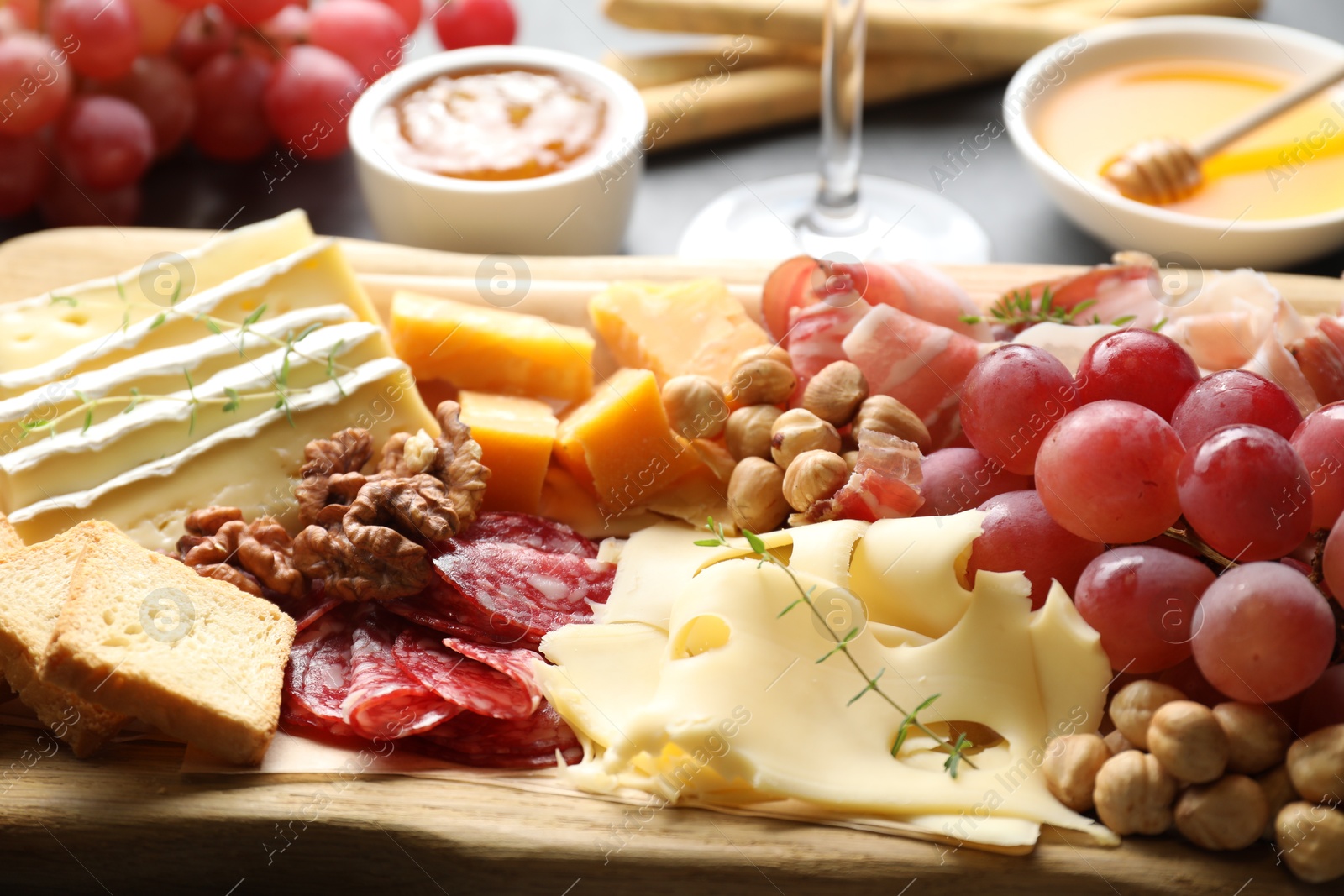 Photo of Different types of cut cheese and other snacks on table, closeup