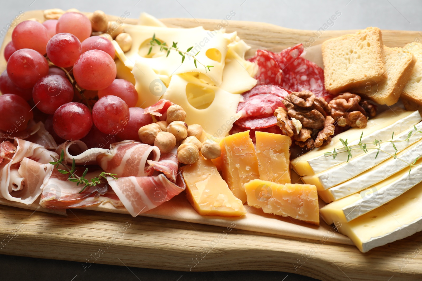 Photo of Different types of cut cheese and other snacks on table, closeup