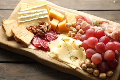 Photo of Different types of cut cheese and other snacks on wooden table, closeup