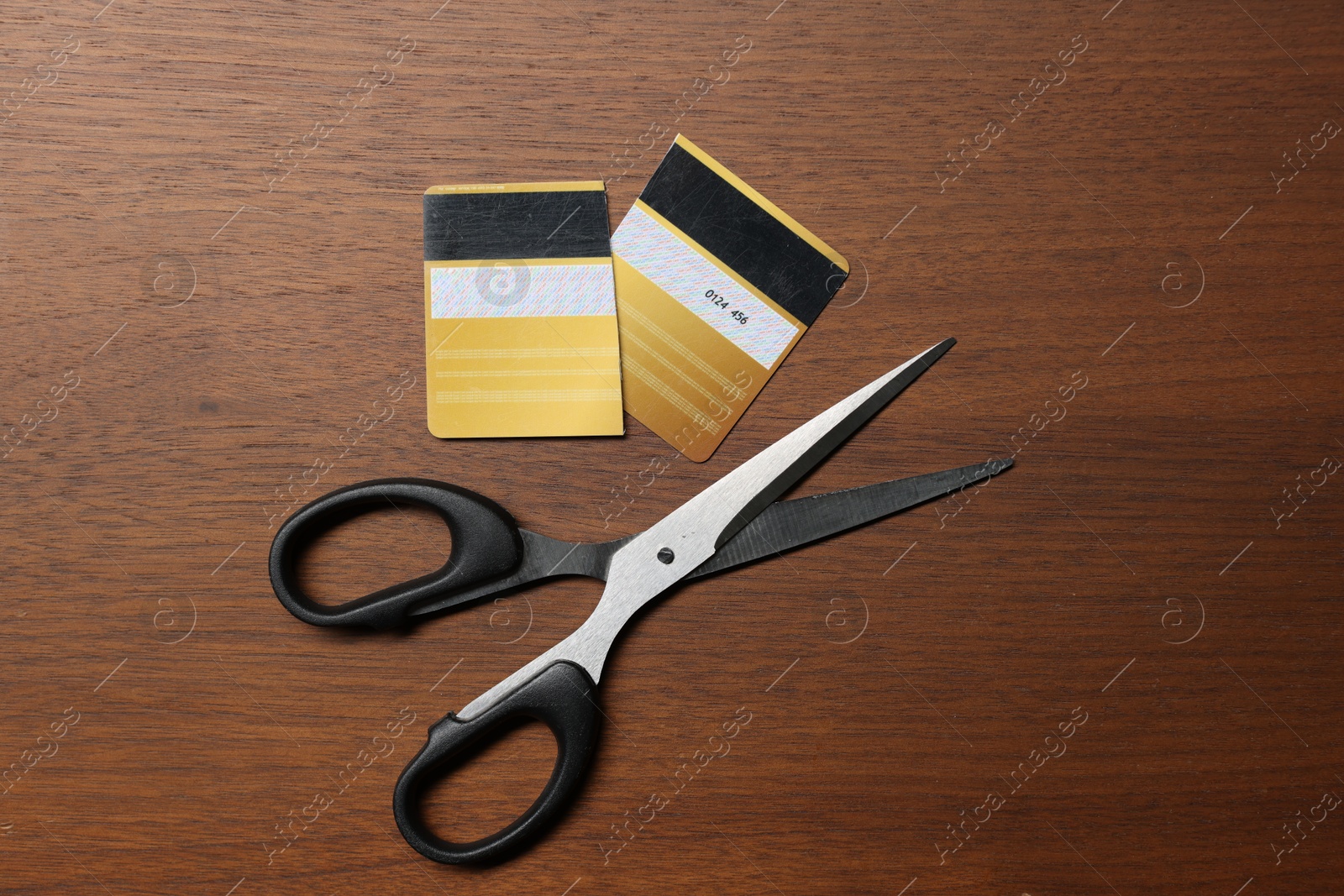 Photo of Pieces of cut credit card and scissors on wooden table, top view