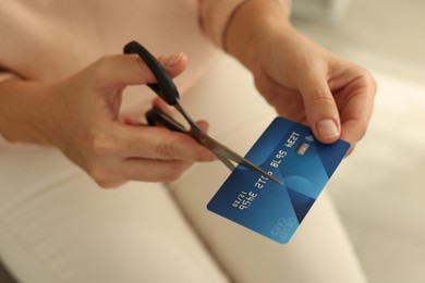 Photo of Woman cutting plastic credit card indoors, closeup