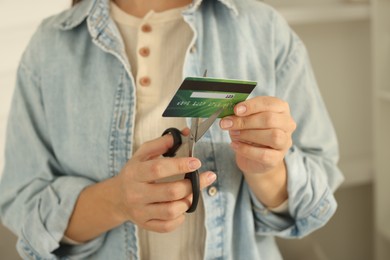 Photo of Woman cutting plastic credit card indoors, closeup