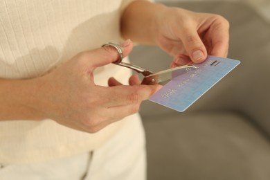 Photo of Woman cutting plastic credit card indoors, closeup