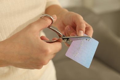 Photo of Woman cutting plastic credit card indoors, closeup