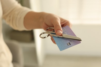 Photo of Woman with credit card and scissors indoors, closeup