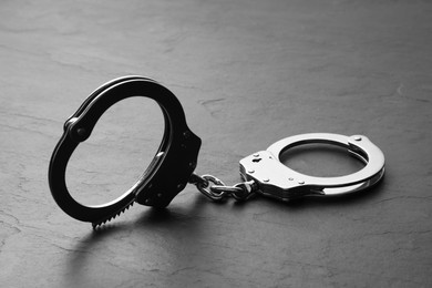 Photo of Classic chain handcuffs on black table, closeup